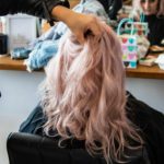 Young lady with baby pink hair, sitting in a hairdresser's chair, having her hair styled