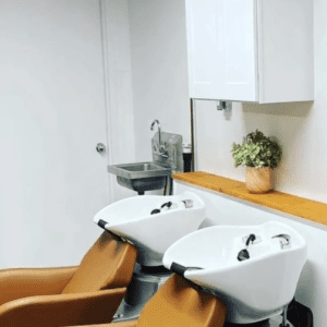 Two shampoo bowls with beige chairs in a salon